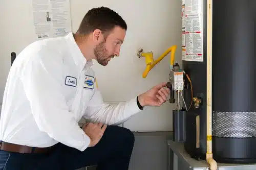Technician inspecting and repairing a tank water heater
