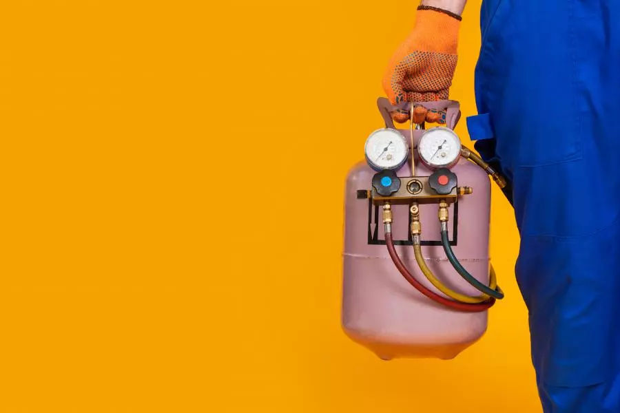 A pink refrigerant canister on a bright orange background