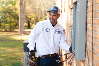 Electrician installing an electrical panel on the side of a home
