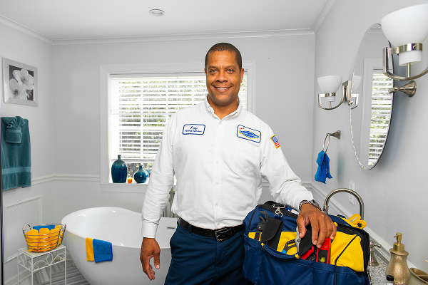 Plumber in bathroom with work bag in front of tb