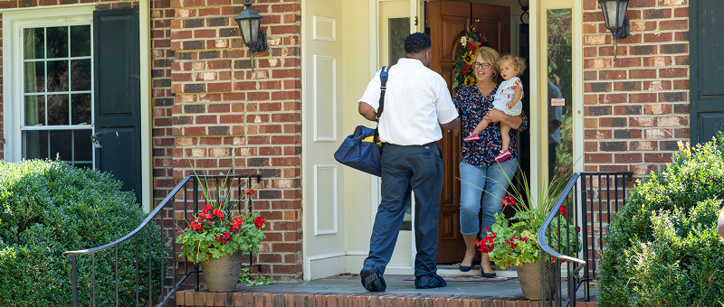Customer holding a child and greeting the tech at the door