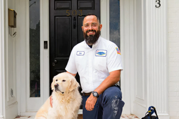 Tech kneeling on porch next to dog