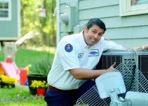 A man leaning on an air conditioner in front of a house.