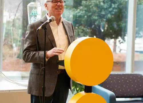 A man standing at a podium in front of a yellow circle.