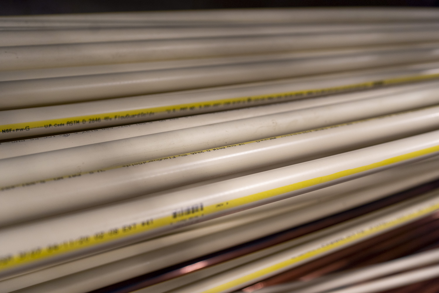 Close-up view of stacked white PVC pipes with yellow markings, arranged horizontally.