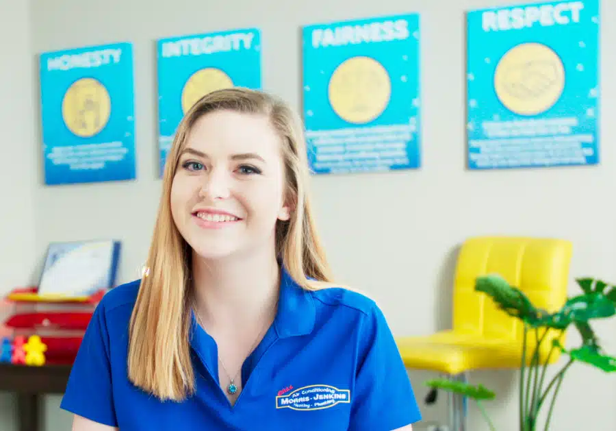 A young woman in a blue shirt sitting at a desk.