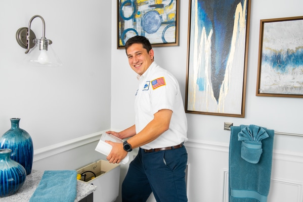 A man standing in a bathroom holding a box.