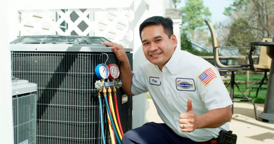 A man standing next to an air conditioning unit.