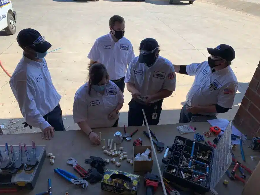 group of plumber trainees around a table with tools and parts.