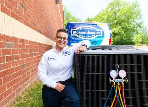 A woman standing next to an air conditioning unit.