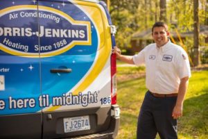 A man standing in front of a jenkins heating and air conditioning van.