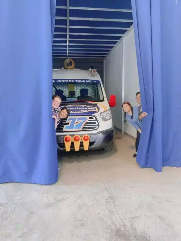 Taya and her coworkers hiding behind curtains.