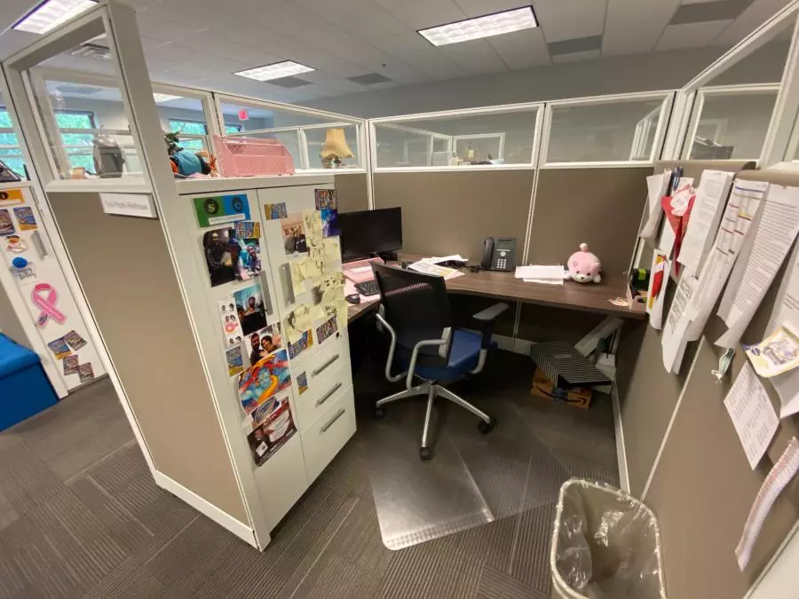 Tayas cubicle and desk decorated with pictures and trinkets.
