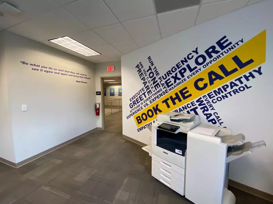 Morris Jenkins office Word Collage wall with words like Explore, urgency, empathy, control, tone, and greet, with "book the call" highlighted in the middle.