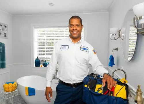 A man standing in front of a bathroom with tools.