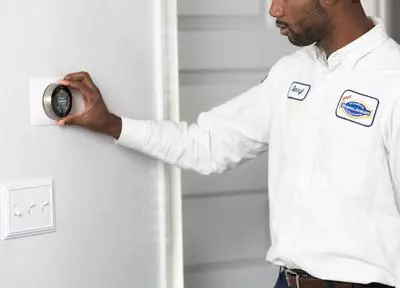 A man installing a thermostat on a wall.