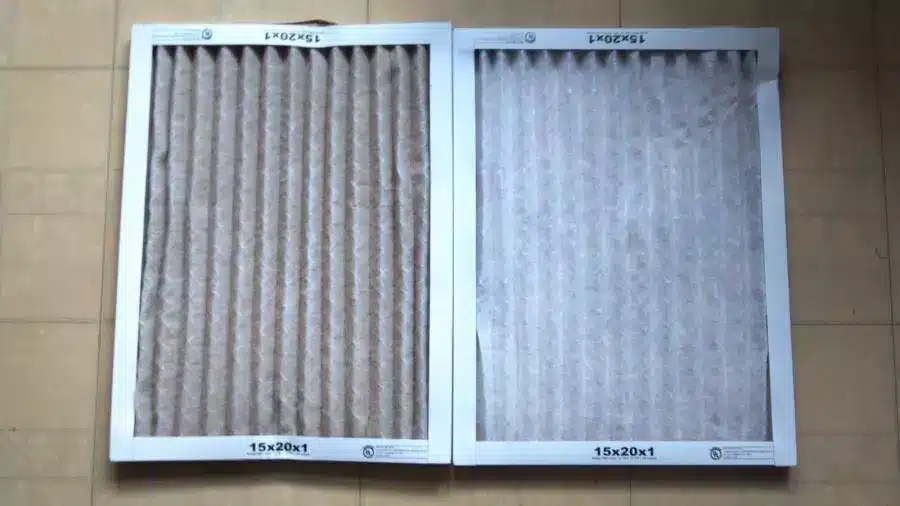Two air filters in a box on a tile floor.
