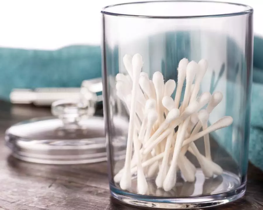 White cotton swabs in a glass on a table.