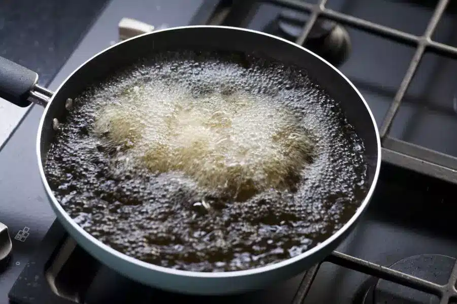 A frying pan on a stove with oil in it.