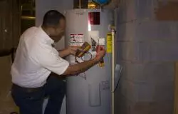 A man working on a water heater in a house.