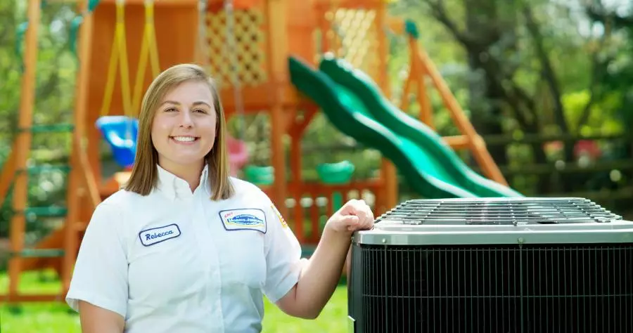 A woman standing in front of an air conditioner.