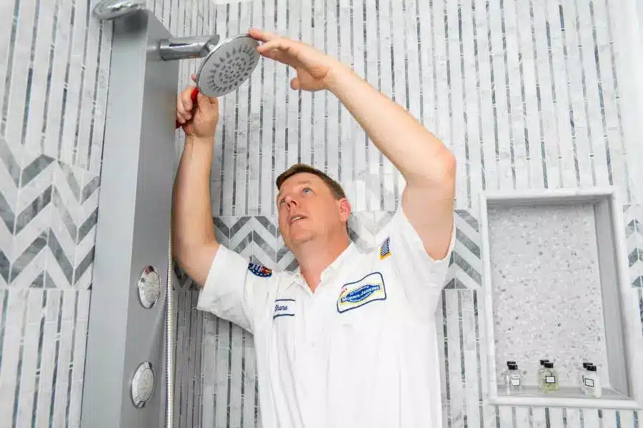 A man installing a shower head in a bathroom.