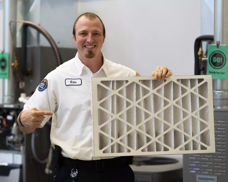 A man holding an air filter in front of a machine.