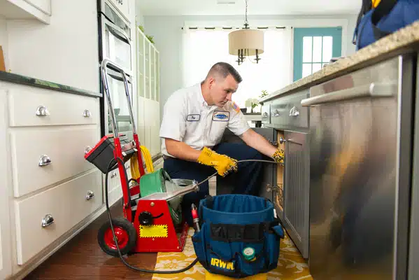 A man cleaning a kitchen with a vacuum.