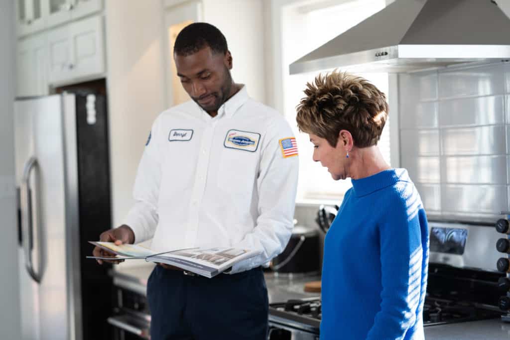 A man and woman looking at a magazine in a kitchen.