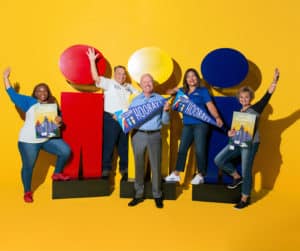A group of people posing in front of a yellow background.