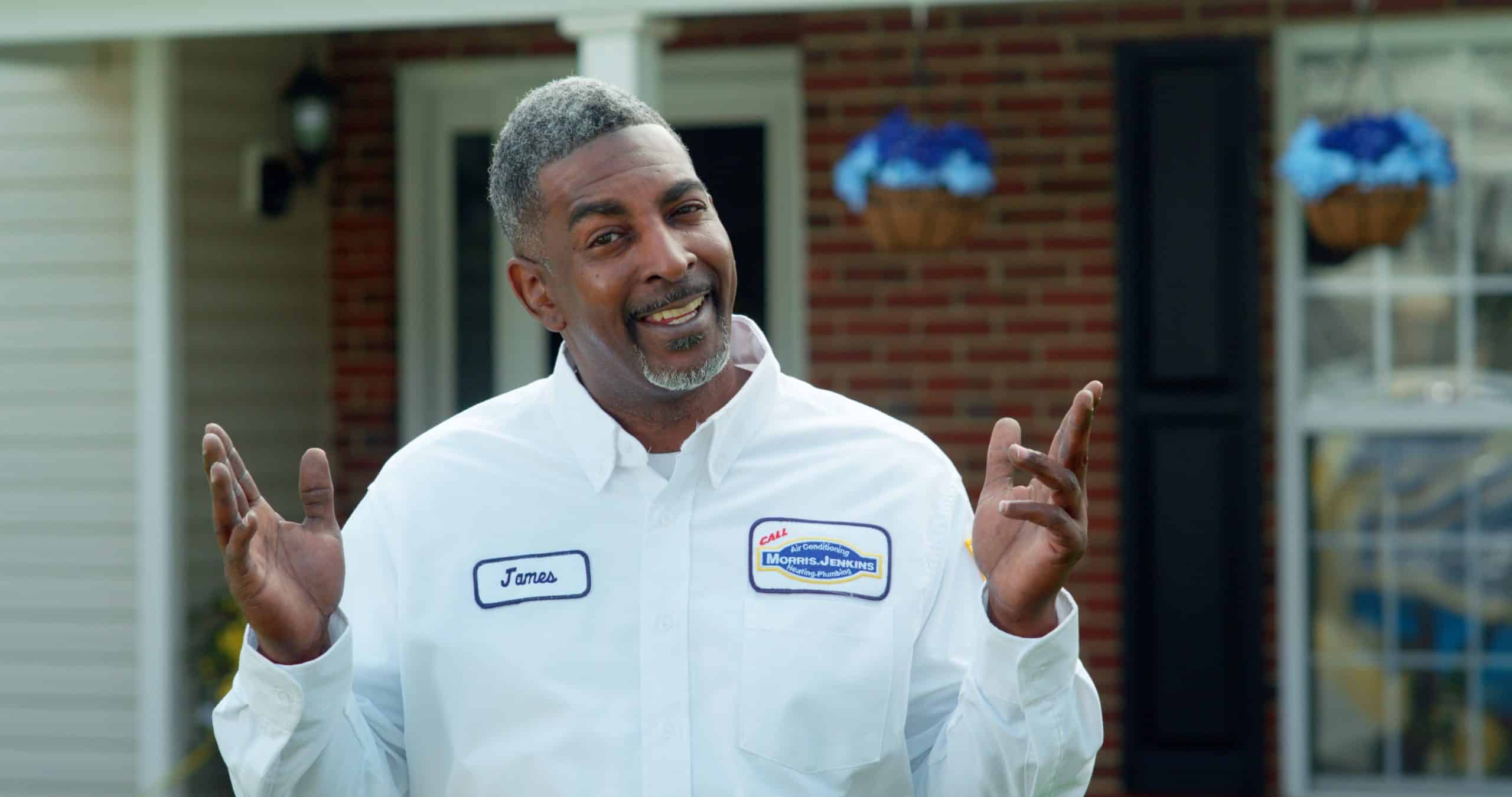 A man in a white shirt standing in front of a house.