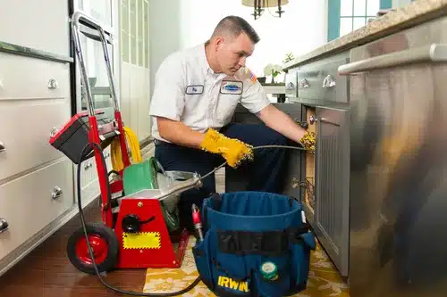 A man cleaning a kitchen with a vacuum.