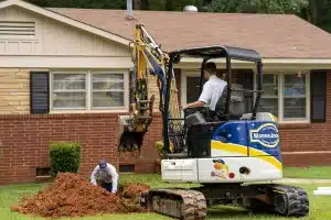 An excavator digging up dirt in front of a house.