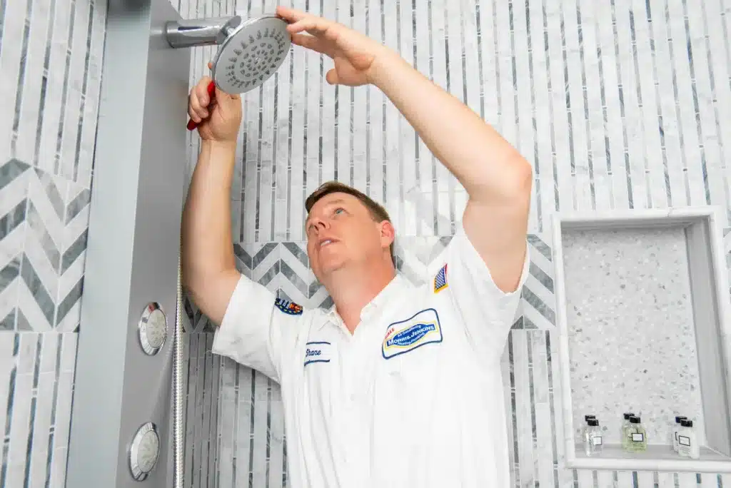 A man installing a shower head in a bathroom.