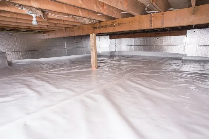 A basement with a white tarp covering the floor.