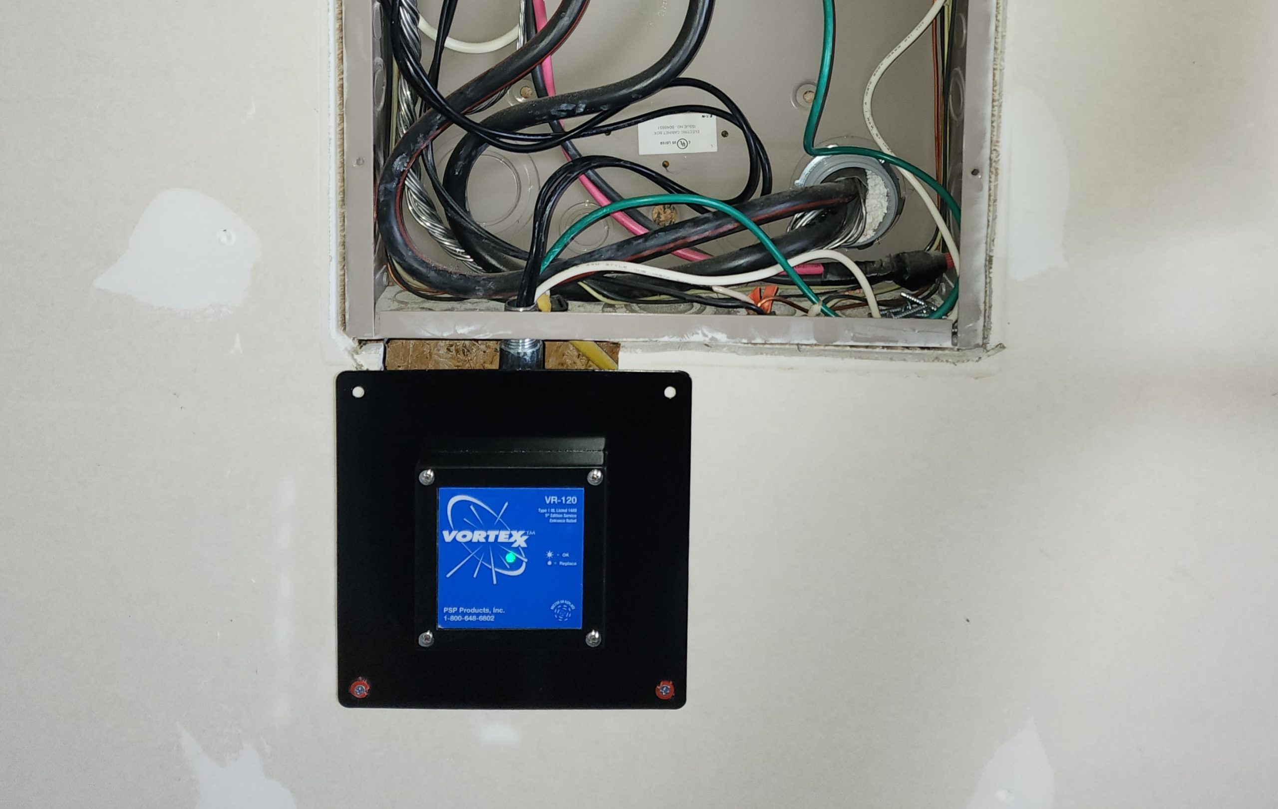 An open electrical box with wires and a mounted black digital control panel displaying "vortex" on its screen.