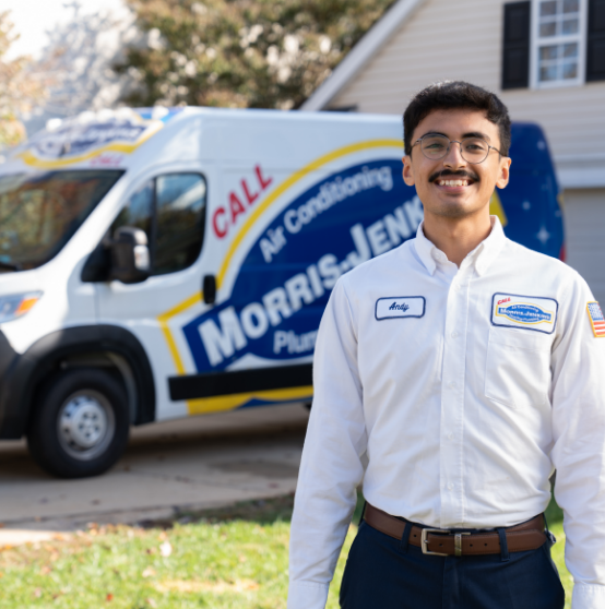 A man in a Morris-Jenkins uniform stands outside in front of a Morris-Jenkins service van and a house on a sunny day.