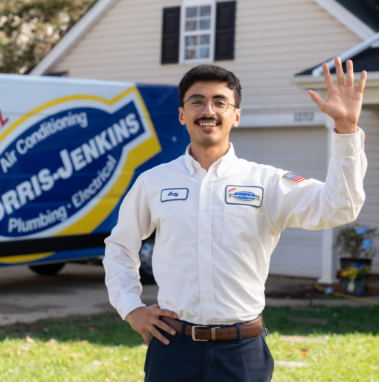 A technician in a uniform with a name tag labeled "Andy" stands outside a house, smiling and waving, with a Harris-Jenkins service van in the background.