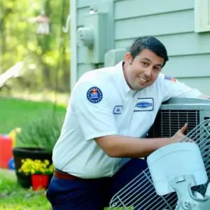 A man leaning on an air conditioner in front of a house.