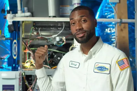 A man in a white shirt standing in front of an air conditioning unit.